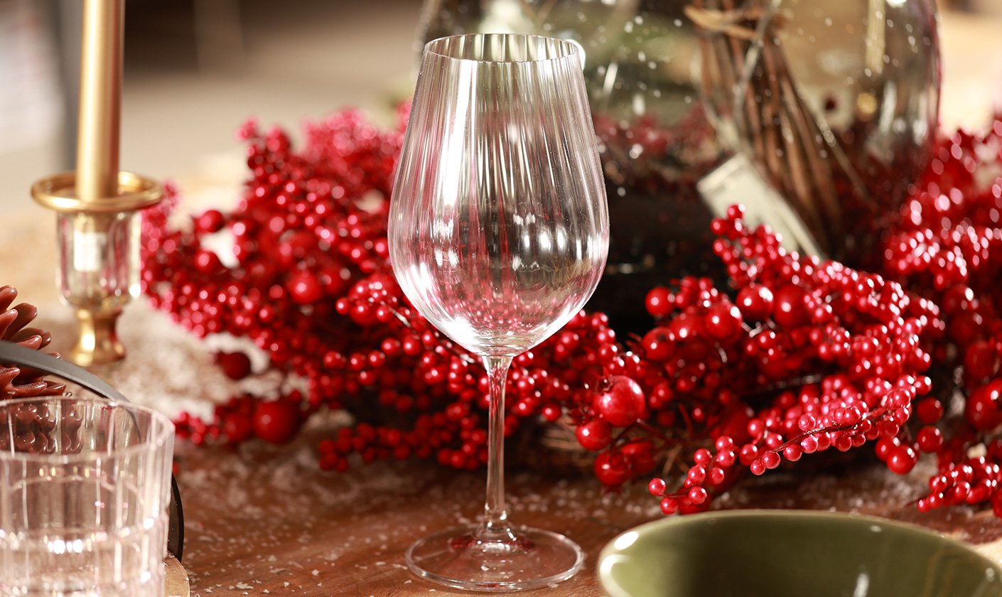 Festive glassware with red decor and candlelight.